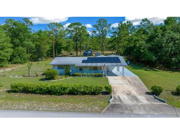 Charming single-story home featuring solar panels, a covered carport, and a well-manicured front yard at 23737 Nw Mallard Ave, Dunnellon, FL 34431
