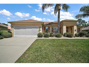 Charming home with manicured lawn, lush landscaping, and a two-car garage in a sunny neighborhood at 12165 Se 91St Ave, Summerfield, FL 34491