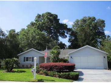 Charming single-story home with well-manicured lawn and mature trees under a clear blue sky at 14272 Sw 112Th Cir, Dunnellon, FL 34432