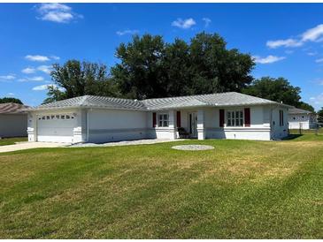 Charming single-story home with a well-maintained lawn and a two-car garage, under a blue sky at 6070 Sw 98Th Loop, Ocala, FL 34476