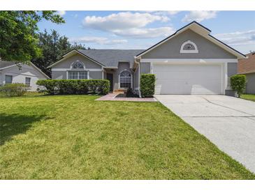 Charming home features a well-manicured lawn, lush shrubs, and a two-car garage, offering great curb appeal at 1317 Ravida Woods Dr, Apopka, FL 32703
