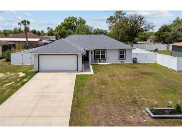 Charming single-story home with a well-manicured lawn, attached garage, and a white picket fence at 14118 Sw 32Nd Terrace Rd, Ocala, FL 34473