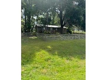 Quaint single-story home featuring a lush green lawn and charming wooden fence at 14121 Nw Highway 225, Reddick, FL 32686