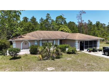 Single story home with neutral paint, brown roof, decorative shrubs, and a screened in lanai at 15920 Sw 49Th Court Rd, Ocala, FL 34473