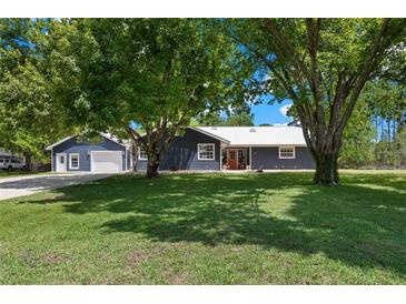 Charming home featuring navy siding, white trim, a metal roof, manicured lawn, and separate garage perfect for cars and storage at 260 Country Circle W Dr, Port Orange, FL 32128