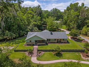 Charming single-story home with stone accents, gray roof, walkway and beautifully manicured lawn, surrounded by mature trees at 400 Se 90Th St, Ocala, FL 34480