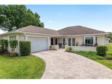 Well-maintained single-story home featuring an attached garage, landscaped front yard, and curved brick driveway at 6858 Sw 111Th Loop, Ocala, FL 34476