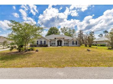 Charming one-story home featuring a manicured lawn and mature trees, offering great curb appeal at 9859 Sw 45Th Ave, Ocala, FL 34476