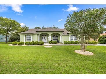 Charming one-story home with a well-manicured lawn, arched entryway, and lush landscaping at 4966 Sw 107Th Loop, Ocala, FL 34476