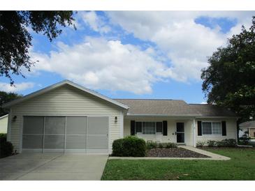 Charming single-story home with a screened garage, manicured lawn, and inviting curb appeal at 11628 Sw 140Th Loop, Dunnellon, FL 34432