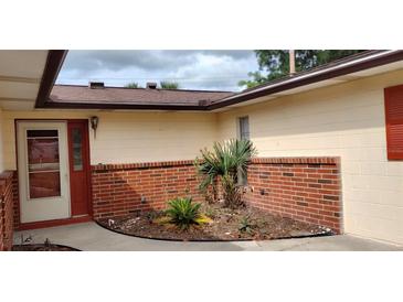 Inviting front entrance with red brick planter and matching door, offering a warm welcome at 12 Brook Pl, Ocala, FL 34472