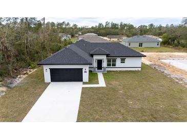 Beautiful single-story home boasts a dark garage, complementary black roof, and a well-manicured lawn at 16890 Sw 39Th Cir, Ocala, FL 34473