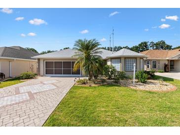 Charming single-story home with a well-manicured lawn, mature landscaping, and brick paver driveway at 17902 Se 115Th Cir, Summerfield, FL 34491