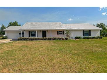 Charming single-story home with a metal roof, attached garage, and well-maintained front yard at 258 Nw 122Nd Ave, Oxford, FL 34484