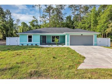 Charming single-story home boasts a manicured lawn, gray roof, an attached two car garage, and a light blue exterior at 4314 Se 131St Ln, Belleview, FL 34420