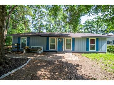 Charming single-story home with blue shutters, brick walkway, and mature trees in a peaceful setting at 5737 Nw 65Th Pl, Ocala, FL 34482