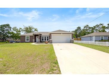 Charming single-story home featuring a manicured lawn, a long driveway, and a two-car garage at 60 Hemlock Trl, Ocala, FL 34472