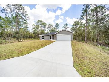 Charming one-story home featuring a long driveway, a two-car garage, and manicured front yard at 24144 Nw Water Oak Ave, Dunnellon, FL 34431
