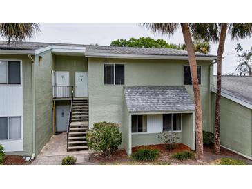 Two-story condo with light-green exterior, stairs to the second floor, and mature trees surrounding the property at 559 Fairway Circle # A, Ocala, FL 34472