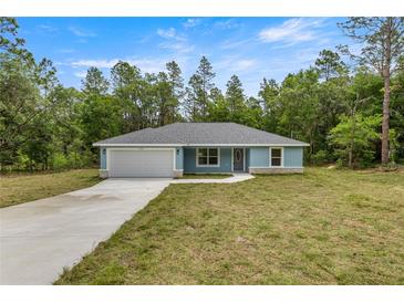 Charming single-story home featuring a well-manicured lawn, attached garage, and freshly painted exterior at 7299 Sw 202 Ct, Dunnellon, FL 34431