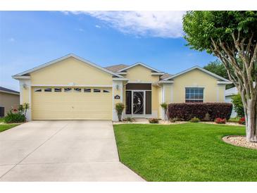 Charming yellow single-story home with a well-manicured lawn and attached two car garage at 1690 Sw 158Th Ln, Ocala, FL 34473
