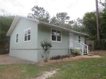 Charming home featuring a light green exterior, well-maintained landscaping, and a welcoming front porch at 5949 Se 164Th Ct, Ocklawaha, FL 32179