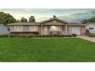 Charming single-story home featuring a well-manicured lawn and welcoming front porch at 8140 Sw 109Th Street Rd, Ocala, FL 34481