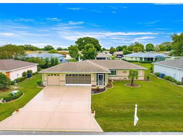 Aerial view of a single-story home with a well-maintained lawn, screened garage and driveway at 9958 Sw 59Th Cir, Ocala, FL 34476