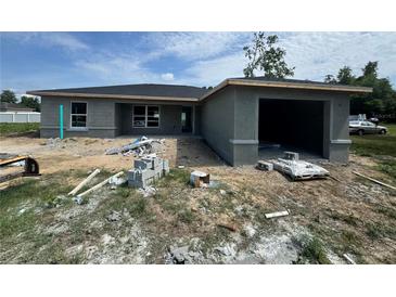 New construction of home with gray concrete exterior and a two-car garage on a partially cleared lot at 1057 Nw 68Th Pl, Ocala, FL 34474