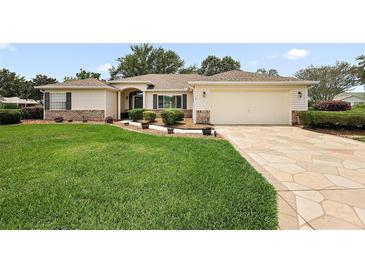 Charming single-story home featuring a well-manicured lawn, decorative stone driveway, and attached two-car garage at 13786 Se 88Th Ct, Summerfield, FL 34491