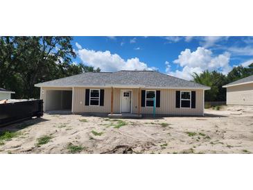 Charming home showcasing neutral siding, black shutters, new roof, and convenient attached carport at 24128 Sw South Lakes Ct, Dunnellon, FL 34431