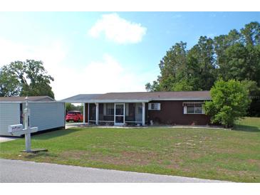 Charming single-story home with a screened-in porch, lush lawn, and mature trees creating a welcoming curb appeal at 9430 Sw 102Nd Pl, Ocala, FL 34481