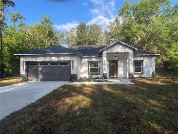 Charming single-story home features a modern design, gray garage door, and a well-manicured front yard at 14540 Se 33Rd Ter, Summerfield, FL 34491