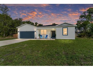 Charming single-story home featuring a well-manicured lawn and an attached garage, all under a vibrant sunset sky at 46 Fisher Lane Ter, Ocklawaha, FL 32179