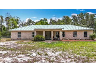 Charming single-story home featuring a light-colored metal roof and a simple, landscaped front yard at 505 Fisher Rd, Ocklawaha, FL 32179