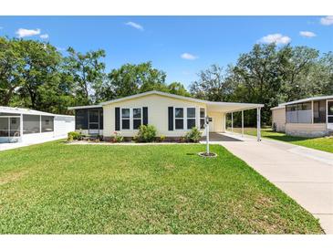 Charming single-story home featuring a lush lawn, carport, and screened entrance at 518 Saint Andrews Blvd, Lady Lake, FL 32159