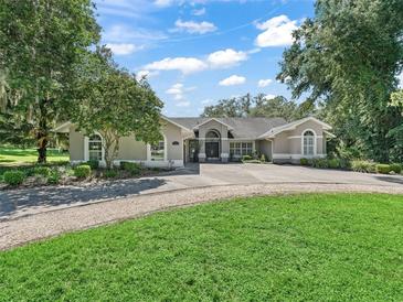 Charming single-story home featuring a circular driveway and mature trees in a lush, green yard at 5714 Nw 80Th Avenue Rd, Ocala, FL 34482