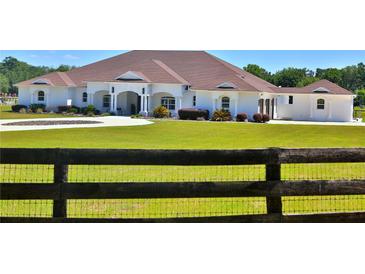 A charming single-story home with a well-manicured lawn and a quaint wooden fence at 6160 W Highway 326, Ocala, FL 34482