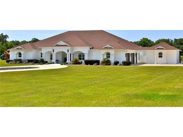 Spacious single-story home boasts a manicured lawn and classic white exterior at 6160 W Highway 326, Ocala, FL 34482