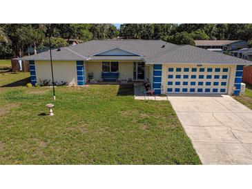 Charming single-story home with a well-maintained lawn, blue accents, and an attached two-car garage at 6211 Se 126Th St, Belleview, FL 34420