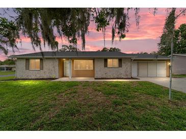 Charming single-story home with a stone facade, lush lawn and beautiful landscaping at sunset at 8463 Sw 108Th Ln, Ocala, FL 34481
