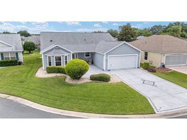 Charming single-story home with a well-manicured lawn, beautiful landscaping, and a two-car garage at 2608 Casso Ct, The Villages, FL 32162