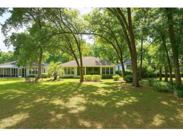Expansive backyard featuring a lush lawn, mature trees, and a screened-in porch, perfect for outdoor living and entertaining at 8926 Sw 192Nd Court Rd, Dunnellon, FL 34432