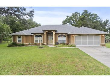 Charming single-story home featuring an arched entryway, well-maintained lawn, and attached two car garage at 10716 Sw 53Rd Cir, Ocala, FL 34476