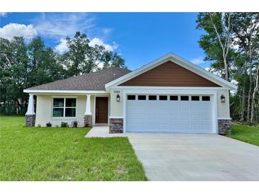 Charming single Gathering home featuring a two car garage, manicured lawn and stone veneer accents at 13303 Sw 106Th Pl, Dunnellon, FL 34432