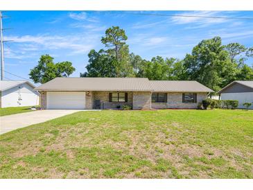 Charming single-story home features a brick facade, metal roof, and attached garage on a well-maintained lawn at 2981 Ne 39Th Pl, Ocala, FL 34479