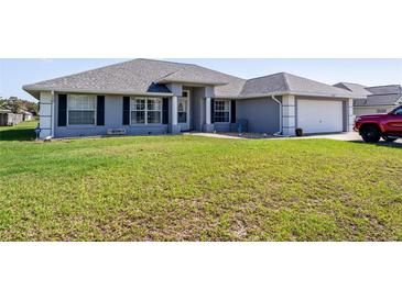 Charming single-story home featuring a well-maintained lawn, grey exterior paint, and a two-car garage at 5920 Sw 88Th Pl, Ocala, FL 34476