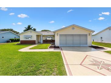 Charming single-story home featuring a manicured lawn, decorative driveway, and attached garage at 17576 Se 96Th Ct, Summerfield, FL 34491