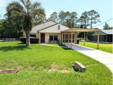 Charming single-story home with a well-maintained lawn, carport, and inviting front entrance at 21298 Sw Peach Blossom St, Dunnellon, FL 34431