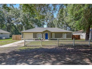 Charming single-story home featuring a well-manicured lawn and inviting blue front door at 3065 Se 142Nd Ln, Summerfield, FL 34491